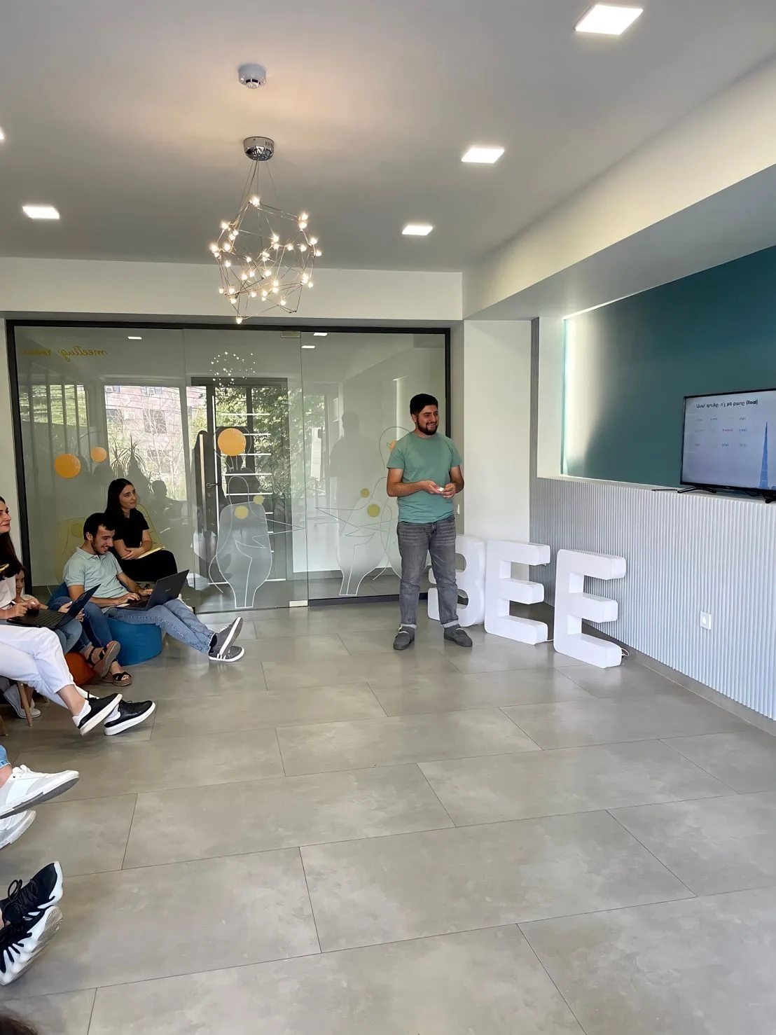 Samvel Antapyan standing in front of the BEE letters while colleagues listen
